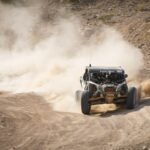 a person driving a buggy on a dirt road