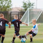 2 men playing soccer during daytime