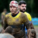 man wearing yellow and blue shirt on mud field during daytime