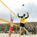 man wearing yellow and black long-sleeved shirt playing volleyball